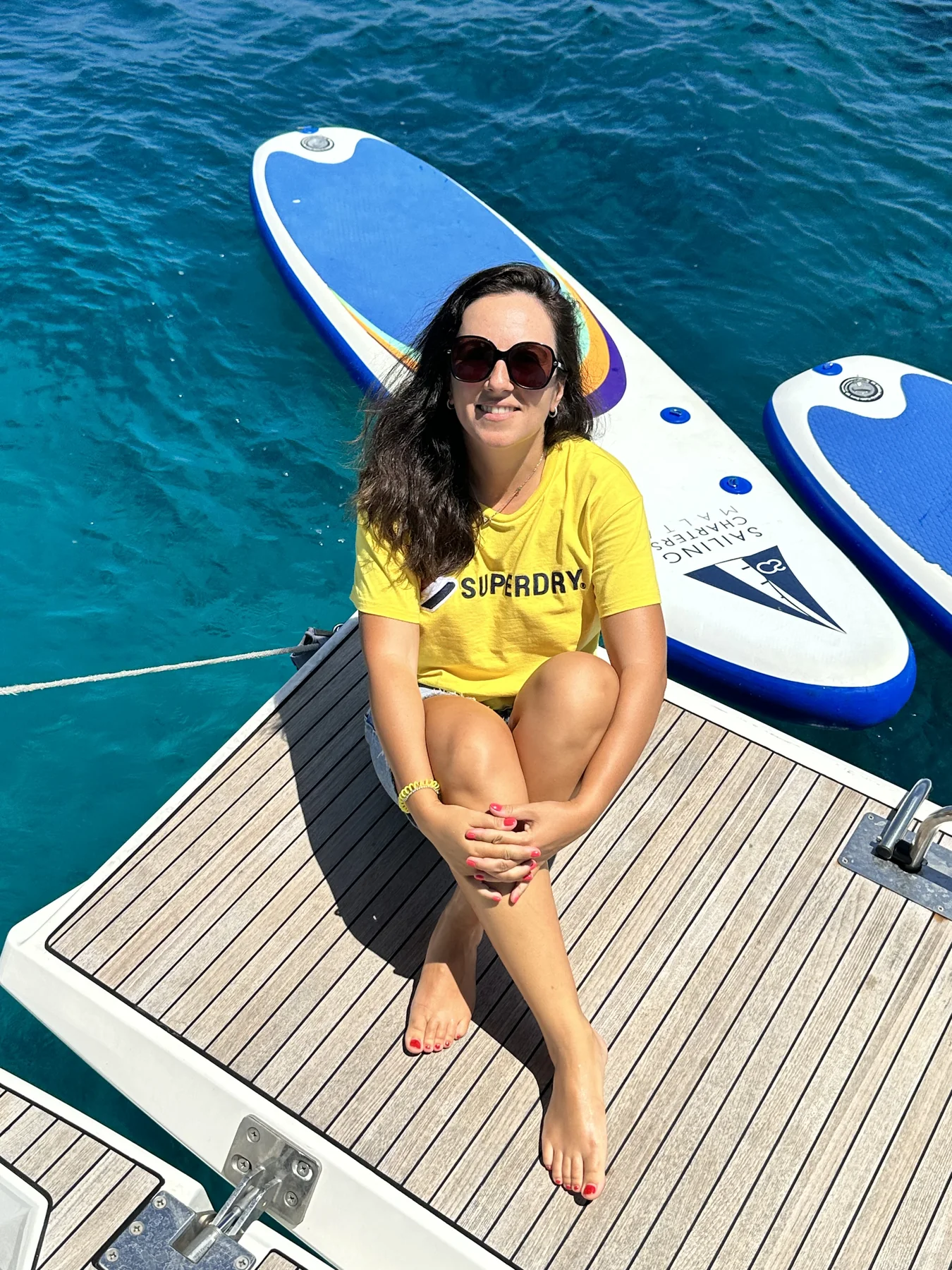 Paddleboard floating beside a boat in clear coastal water.